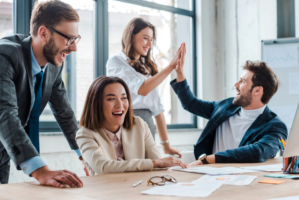 Happy business team celebrating increase of engagement by giving each other high fives. 