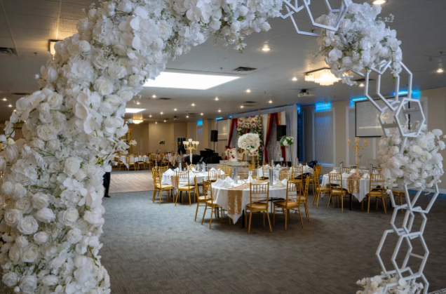 Heritage Banquet Hall set with round tables, hanging greenery garlands, and soft blue ambient lighting for a reception