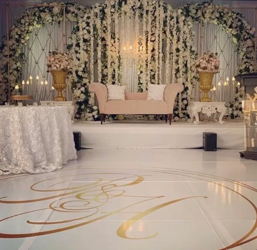 White and gold wedding ceremony backdrop with draped fabric and floral accents at Heritage Banquet Hall